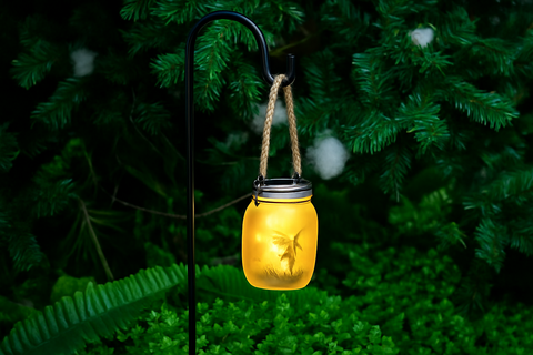 Solar-powered lantern hanging from a tree with a glowing yellow light.