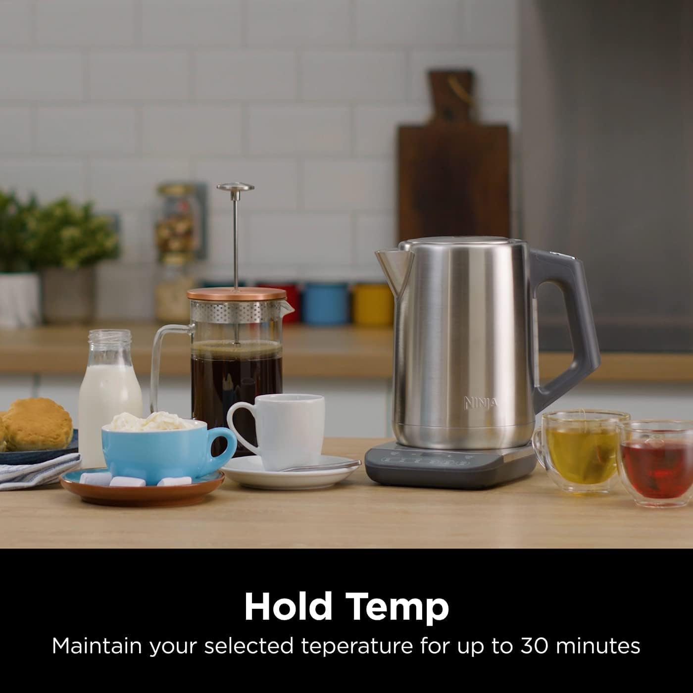 Stainless steel kettle on a kitchen counter with coffee and tea, text 'Hold Temp' displayed.
