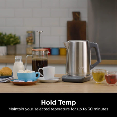 Stainless steel kettle on a kitchen counter with coffee and tea, text 'Hold Temp' displayed.