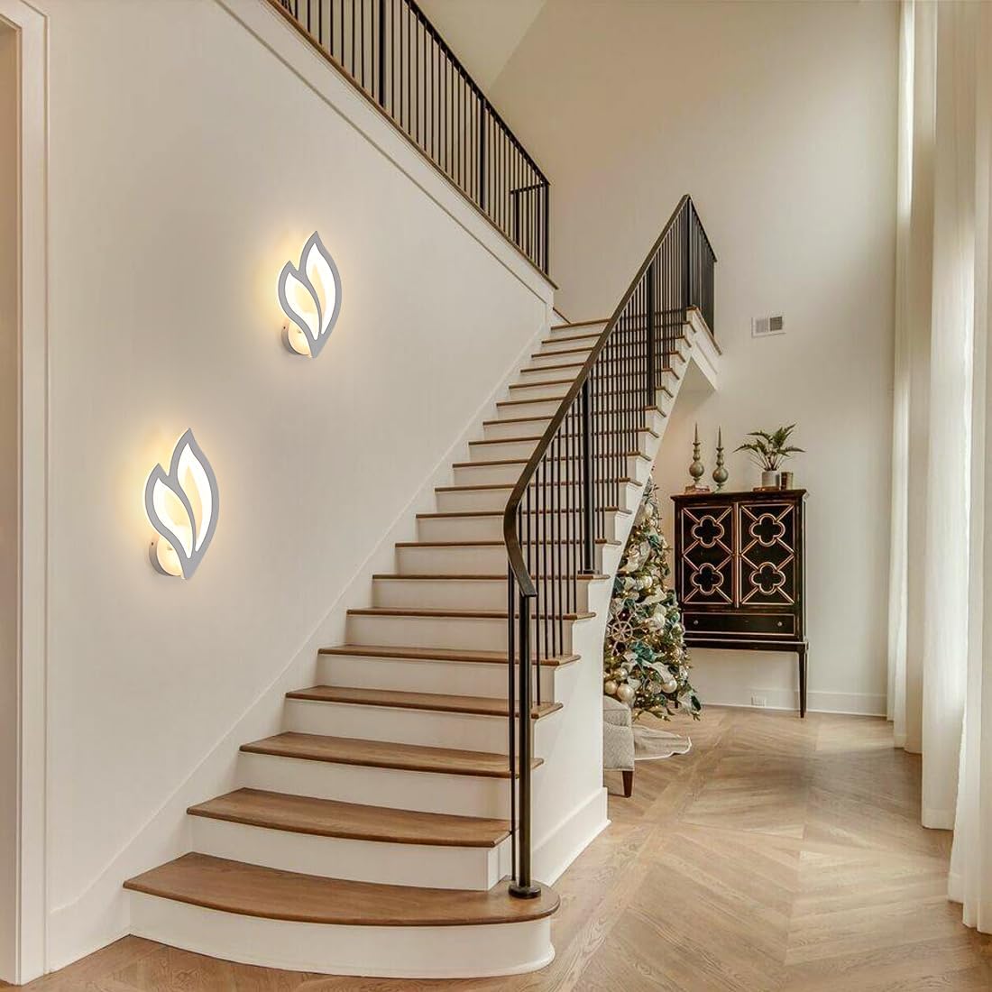 Staircase with wall lights and a decorated Christmas tree in a home interior.