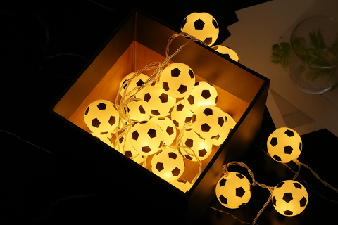 String lights shaped like soccer balls in a box with a dark background