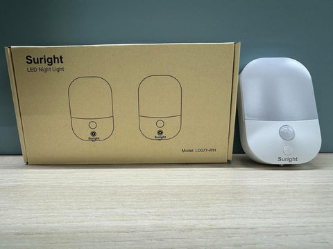 Suright LED night light next to its packaging on a wooden surface with a dark background