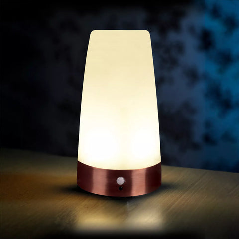 Table lamp with a warm glow on a wooden surface against a dark background