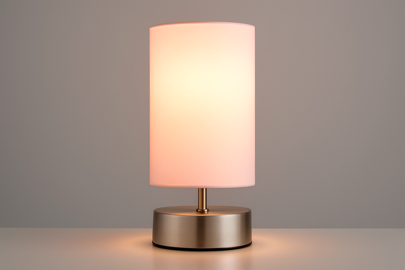 Table lamp with a white shade and metallic base on a gray background