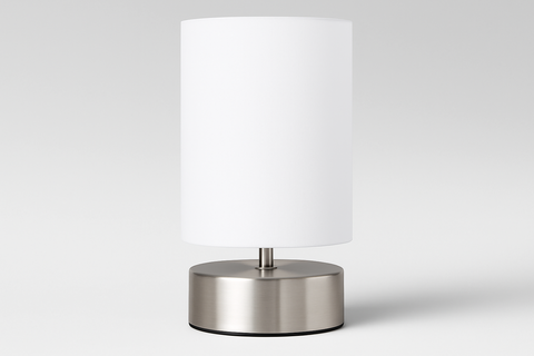 Table lamp with a white shade and metallic base on a light gray background