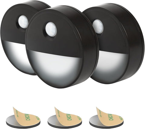 Three black motion sensor lights with adhesive pads on a white background