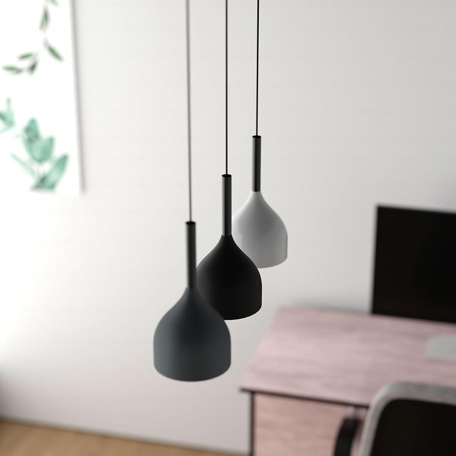 Three black pendant lights hanging against a white wall with a blurred background.