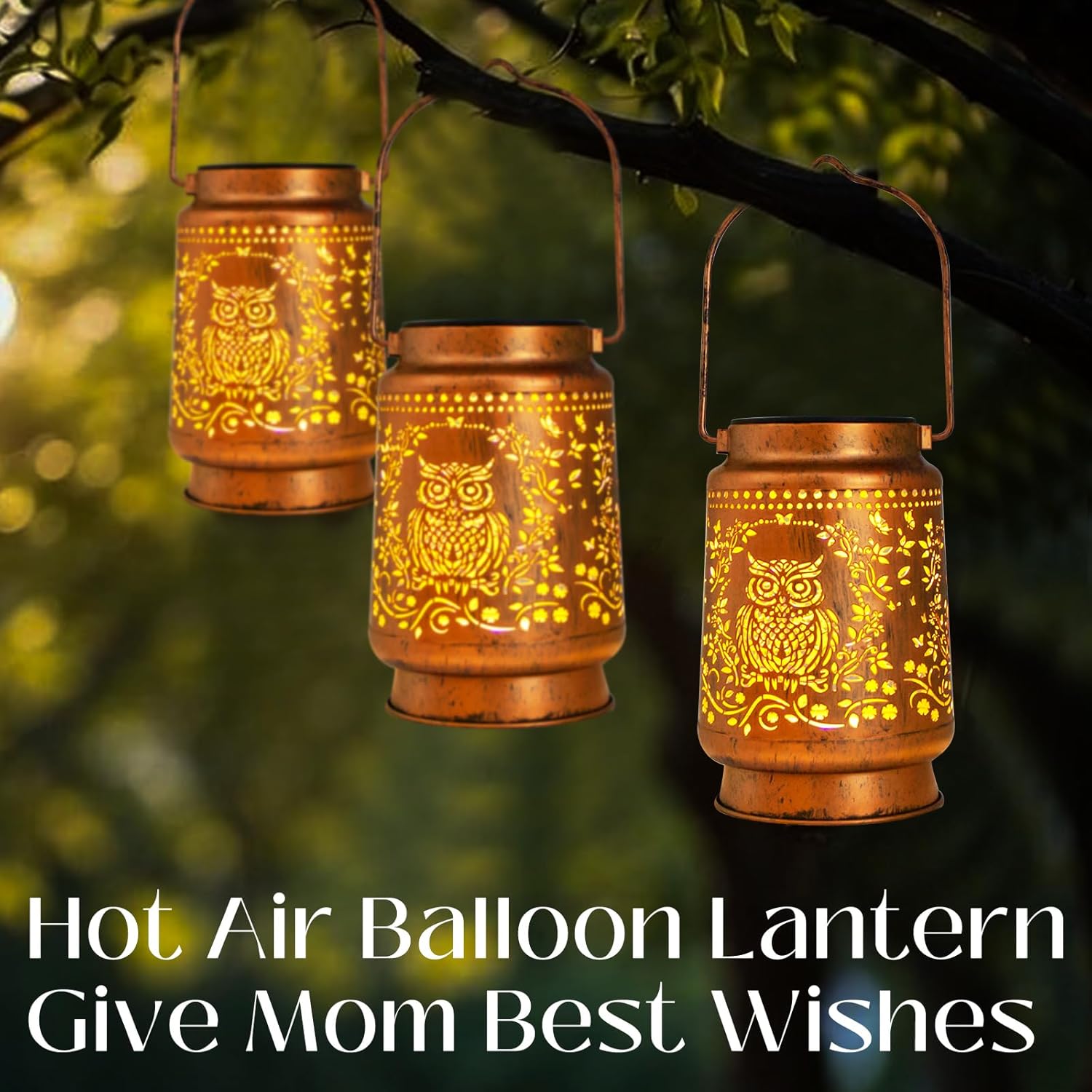 Three copper-colored lanterns with owl designs hanging from a tree branch.