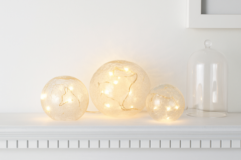 Three glass bulb lights on a white surface with a white frame in the background