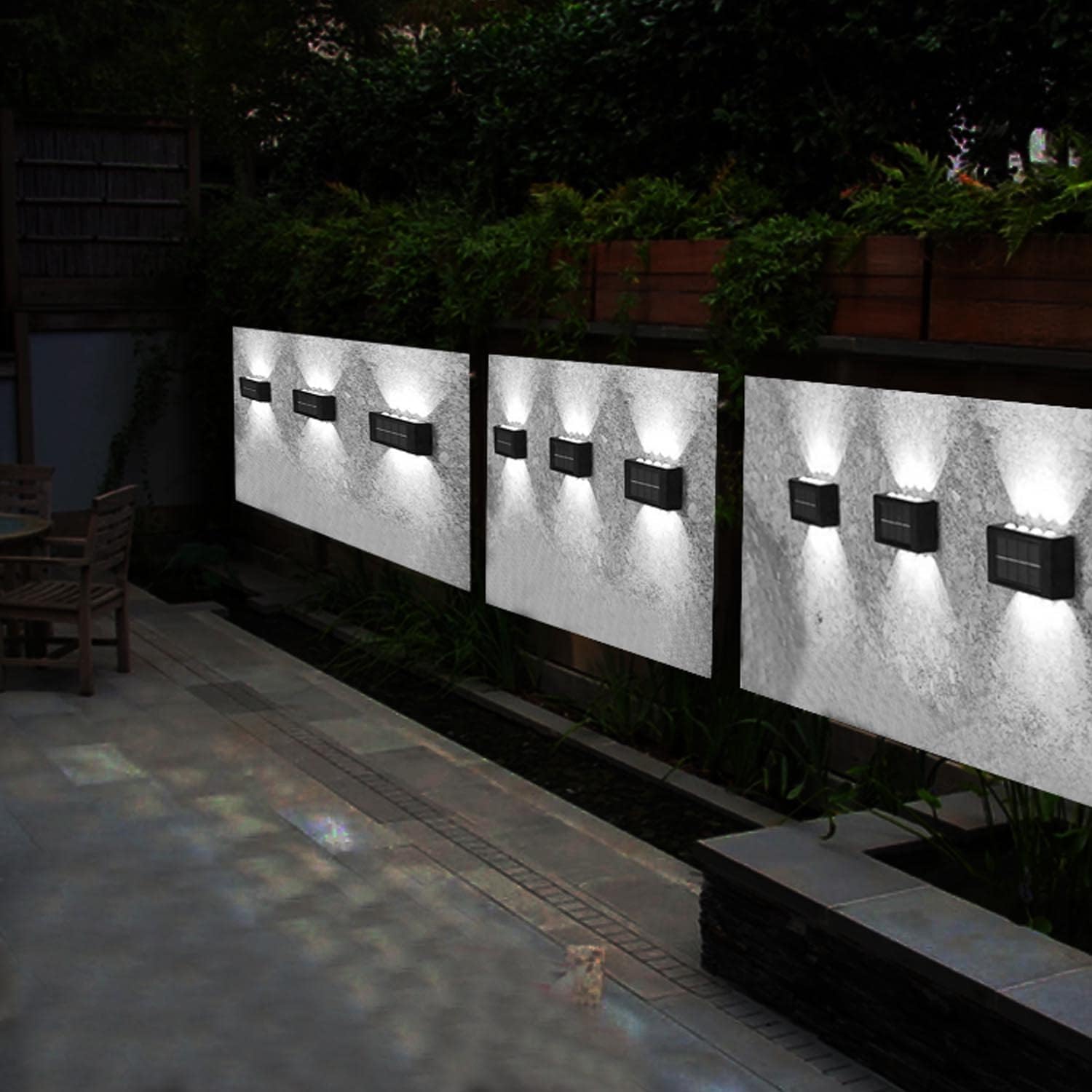 Three outdoor wall lights on a concrete wall with a garden and pathway in the background.
