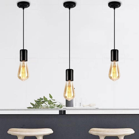 Three pendant lights with vintage-style bulbs hanging above a table with decorative elements.