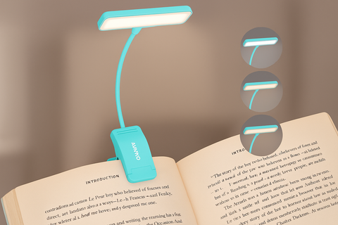 Turquoise LED reading lamp on an open book with a blurred background
