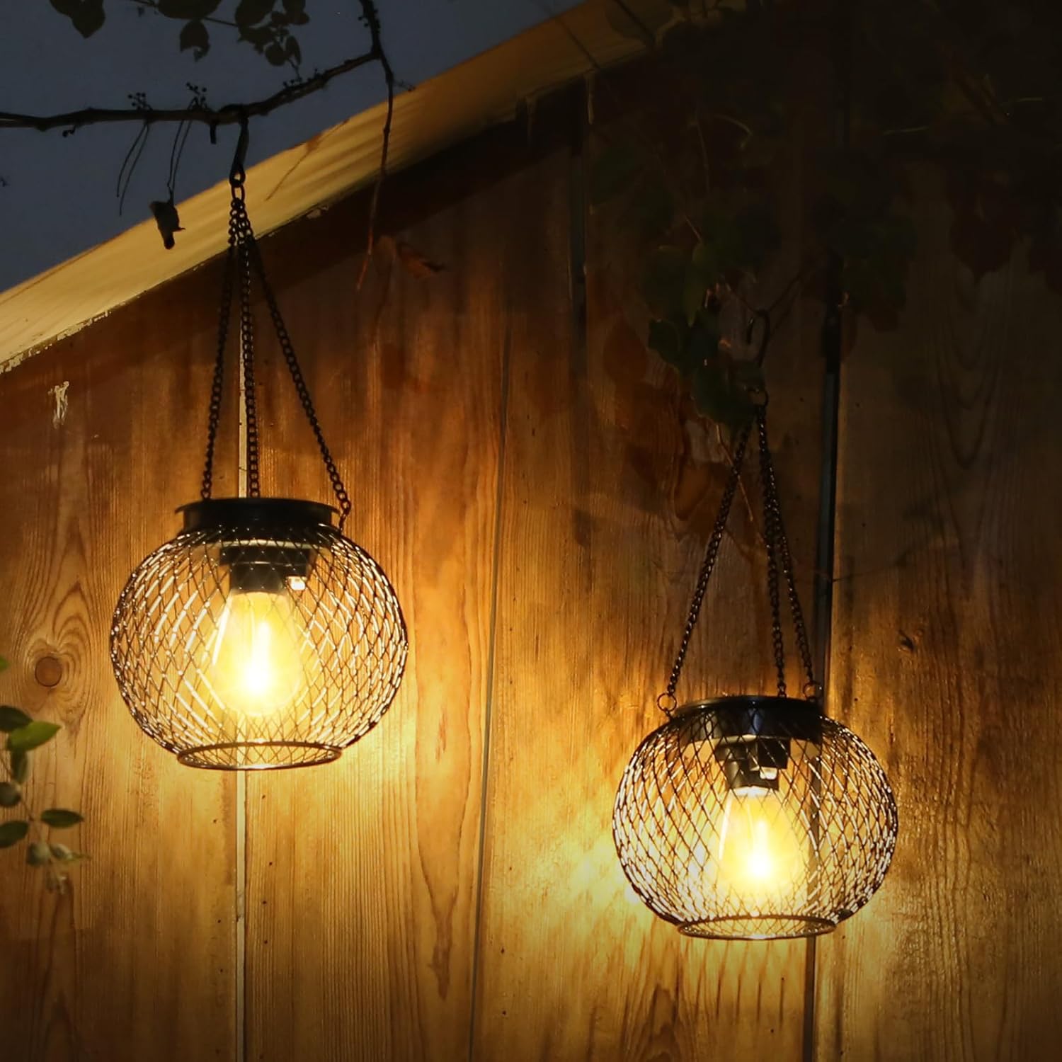 Two hanging wire mesh lights glowing against a wooden wall.