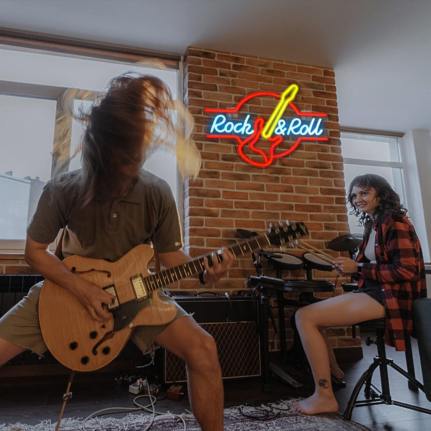 Two musicians playing guitar and drums in a room with a 'Rock & Roll' neon sign.