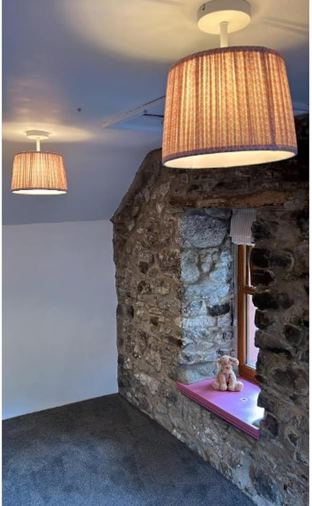 Two pendant lights hanging above a stone wall with a small window and teddy bear.