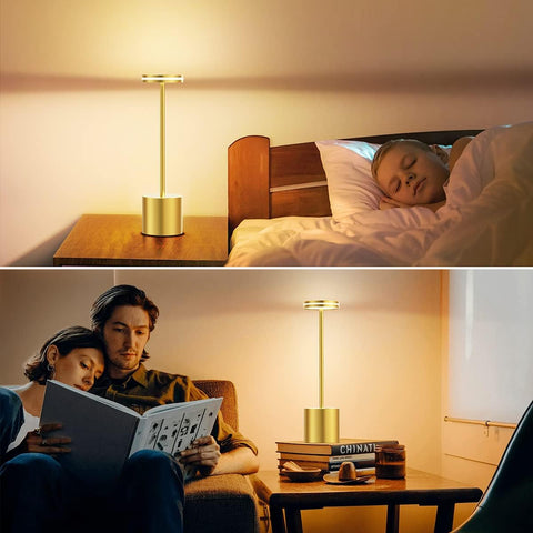 Two people reading a book together with a lamp on a table between them.