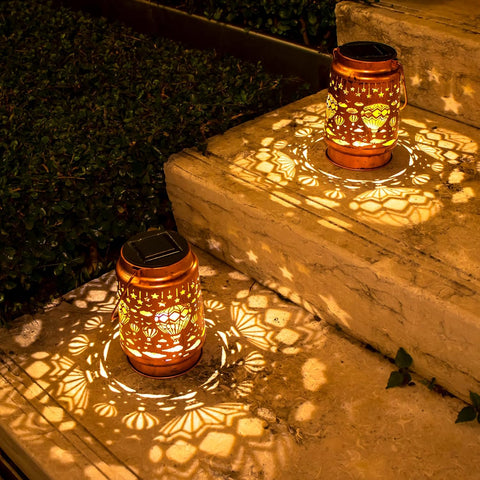 Two solar lanterns casting decorative shadows on stone steps at night.