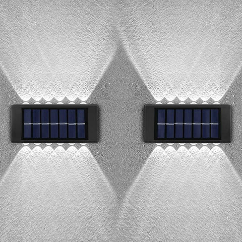 Two solar panels mounted on a textured white wall.