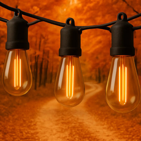 Three illuminated light bulbs on a string against an orange background