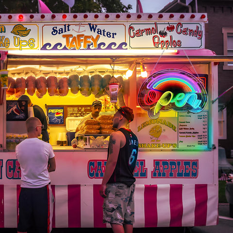 Vibrant food truck with colorful signage and a rainbow-colored lemonade stand sign.