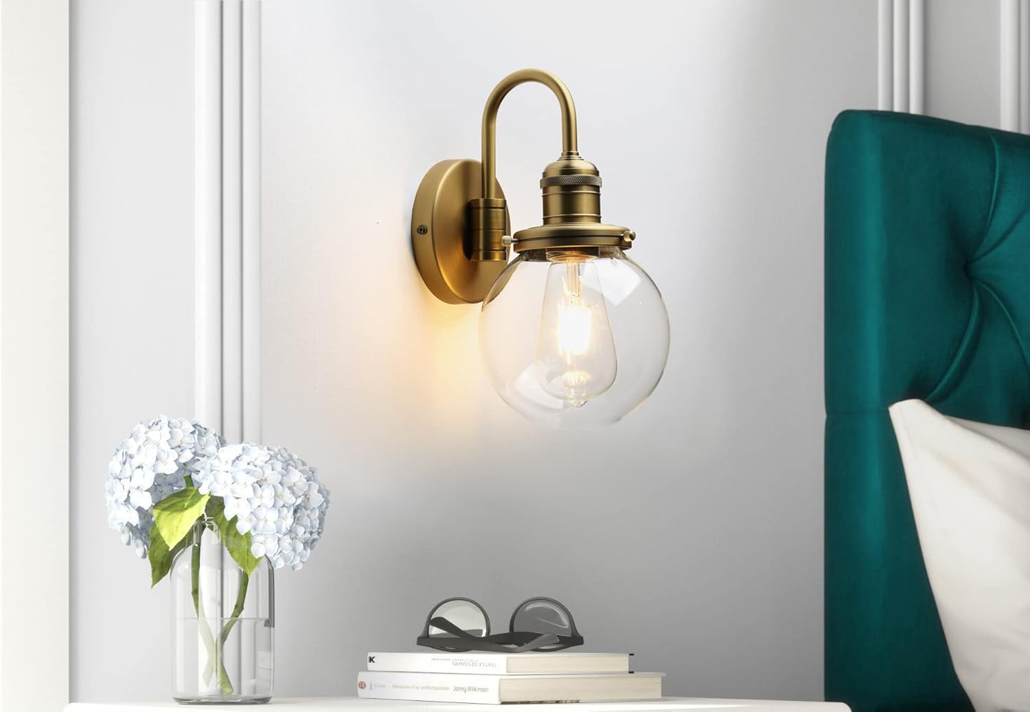Vintage-style wall sconce with a clear light bulb on a white wall next to a teal headboard.