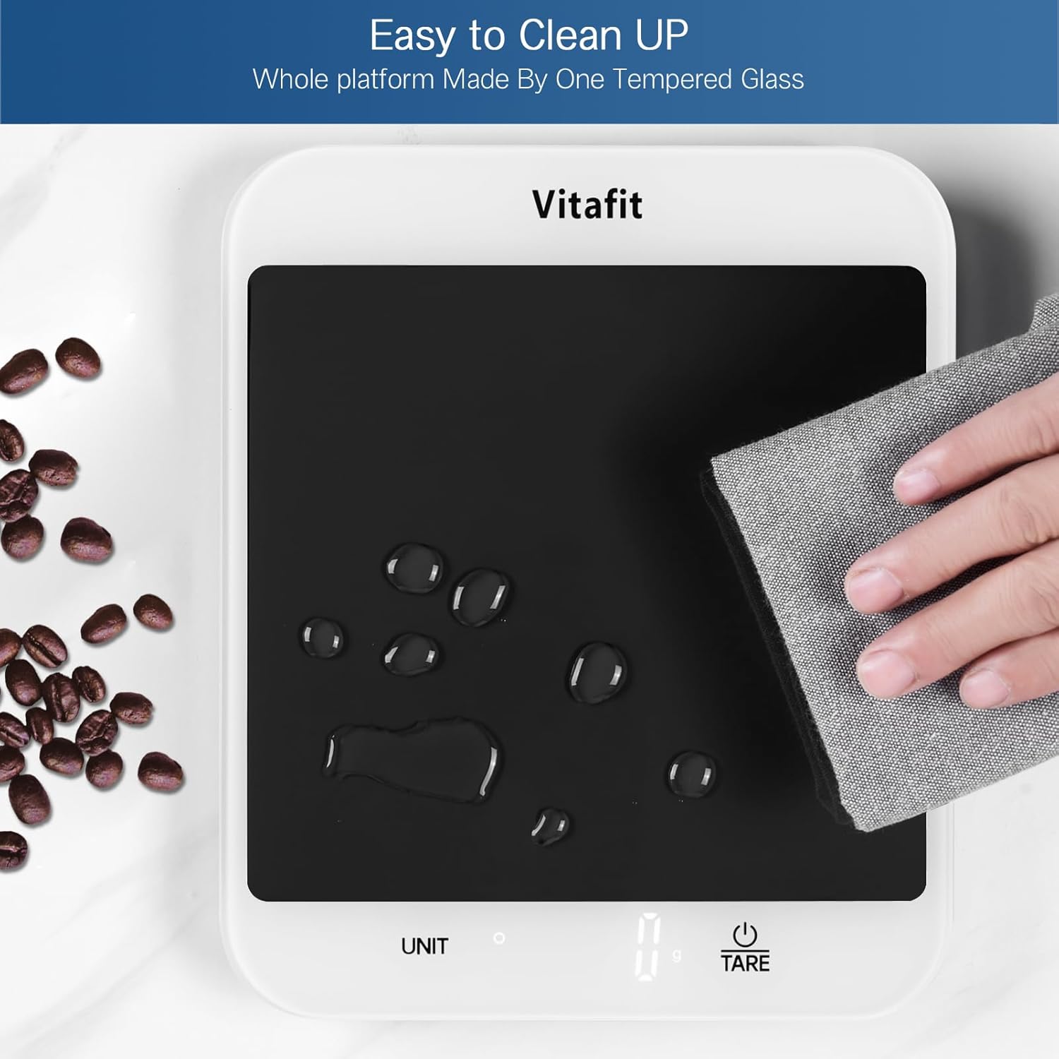 Vitafit platform with a hand cleaning it using a gray cloth, surrounded by coffee beans.