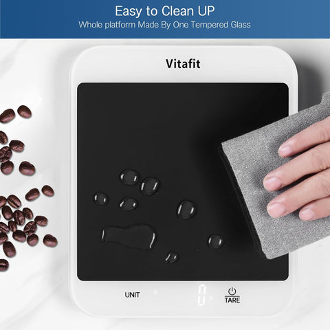 Vitafit platform with a hand cleaning it using a gray cloth, surrounded by coffee beans.