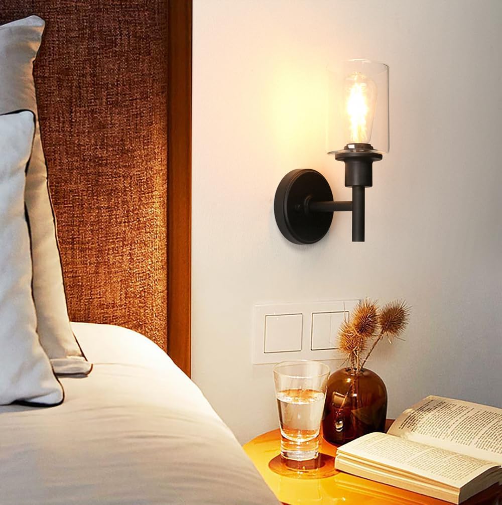 Wall-mounted lamp illuminating a bedside table with a glass of water, vase, and open book.