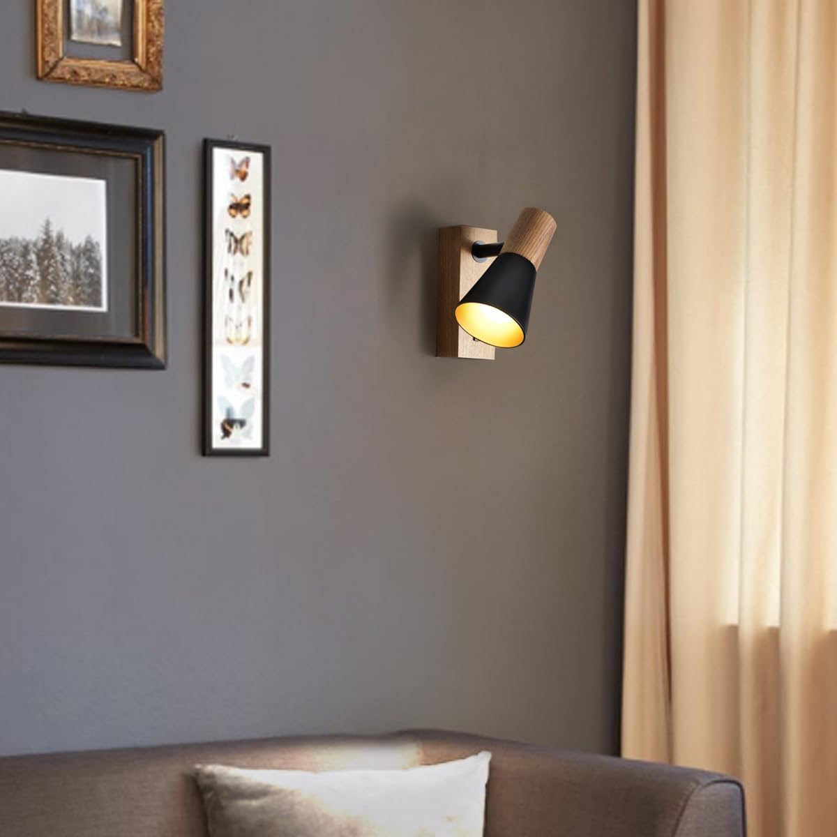 Wall-mounted light fixture on a gray wall with framed pictures and a sofa in the foreground.