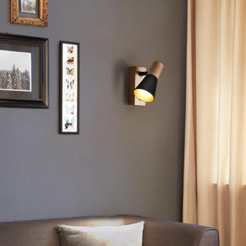 Wall-mounted light fixture on a gray wall with framed pictures and a sofa in the foreground.