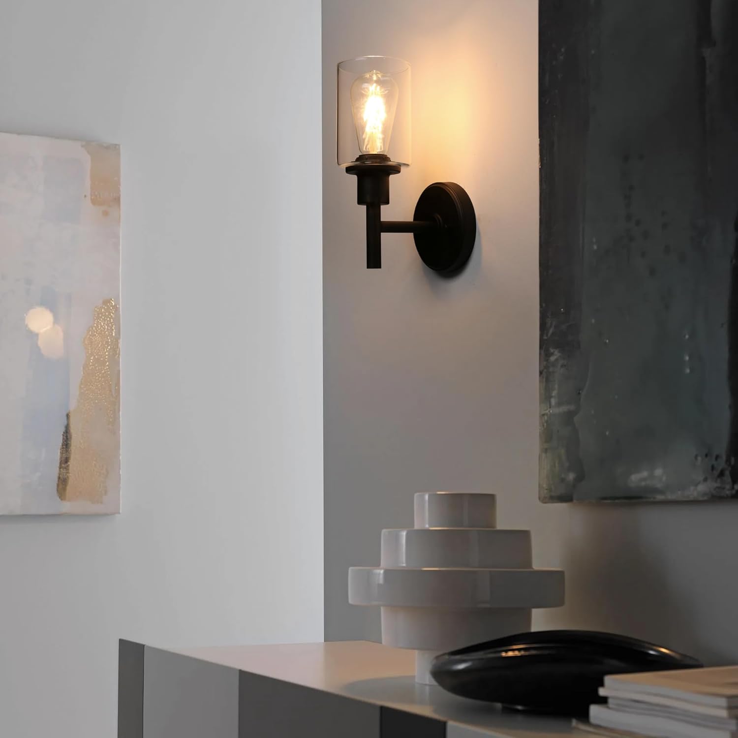 Wall-mounted light fixture on a white wall with decorative items below.
