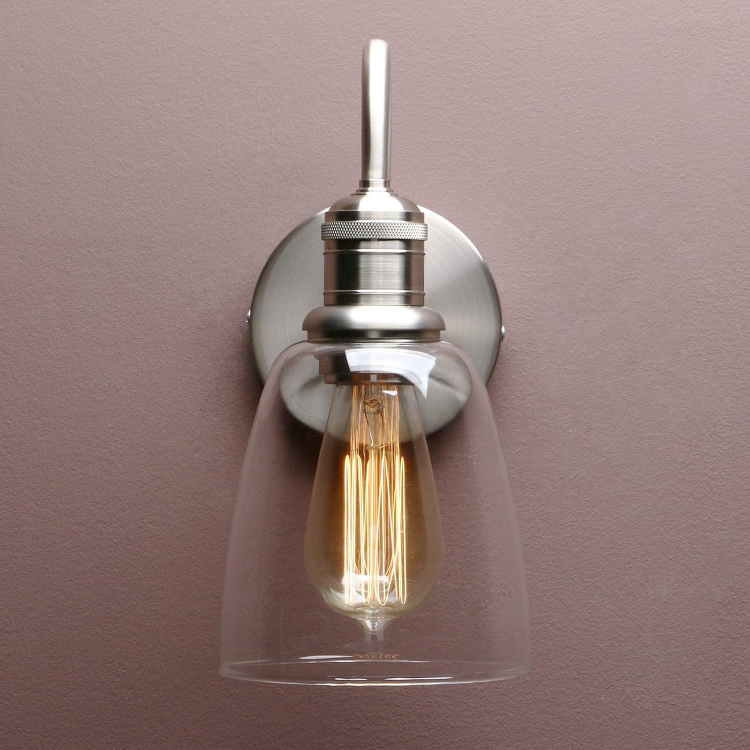 Wall-mounted light fixture with a clear glass shade and visible bulb against a purple wall.