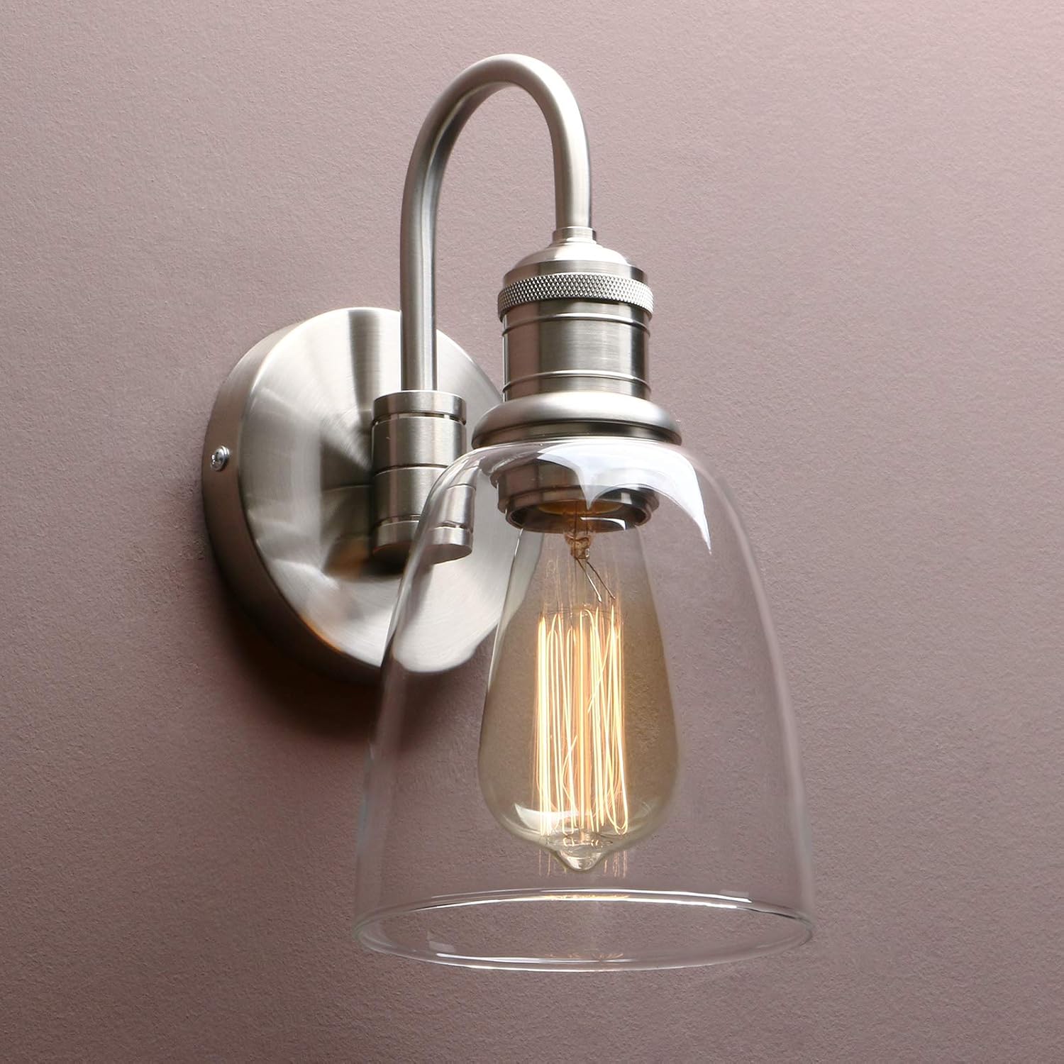 Wall-mounted light fixture with clear glass shade and visible bulb against a plain background