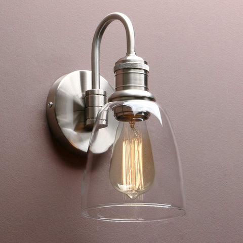 Wall-mounted light fixture with clear glass shade and visible bulb against a plain background