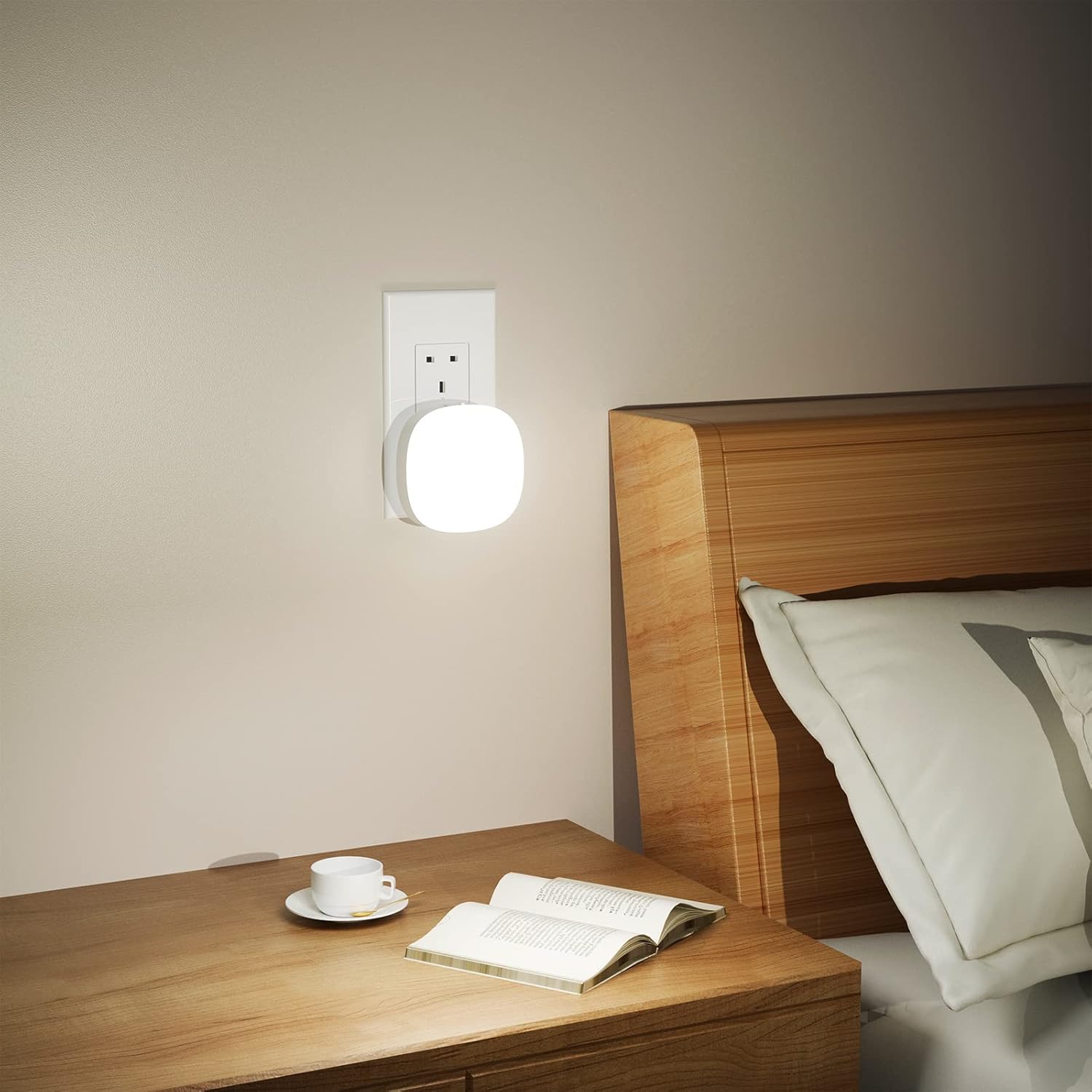 Wall-mounted night light above a wooden bedside table with a book and cup.