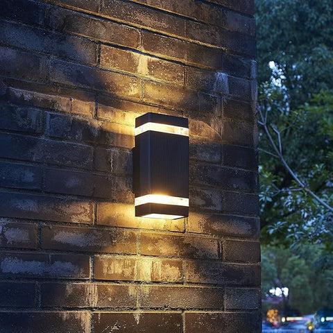 Wall-mounted outdoor light fixture on a brick wall at night.