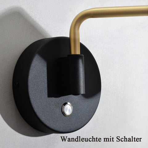 Wall light fixture with black base and gold arm on a gray background
