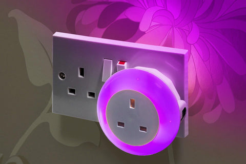 Wall socket with a glowing purple night light on a floral background