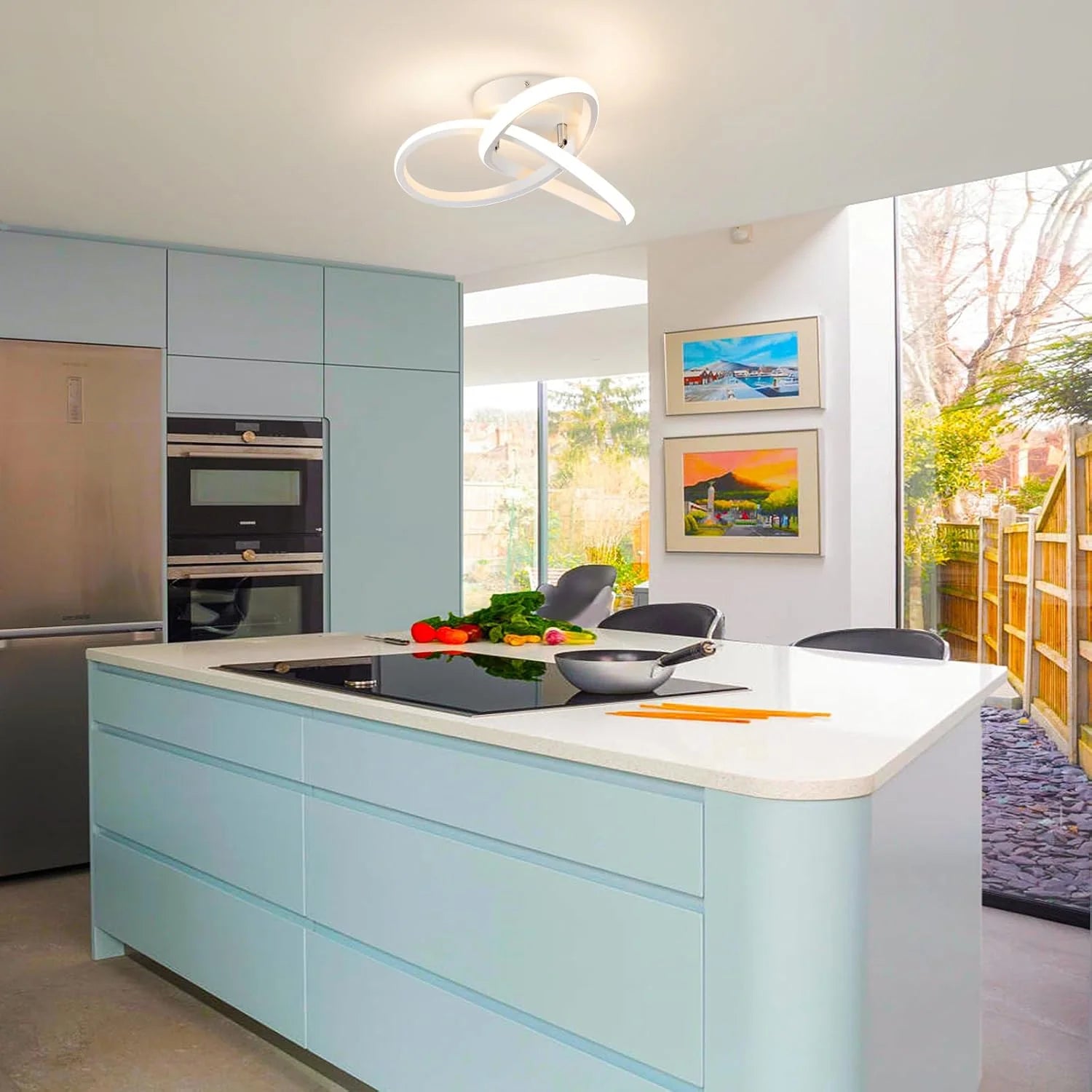 Modern kitchen with light blue cabinets, white countertops, and a large window.