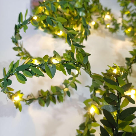Decorative wreath with green leaves and small lights on a white background