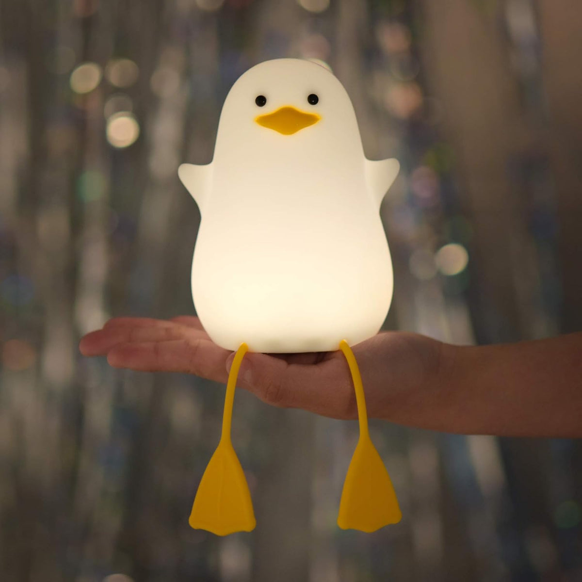 White duck-shaped night light held in a hand with a blurred background