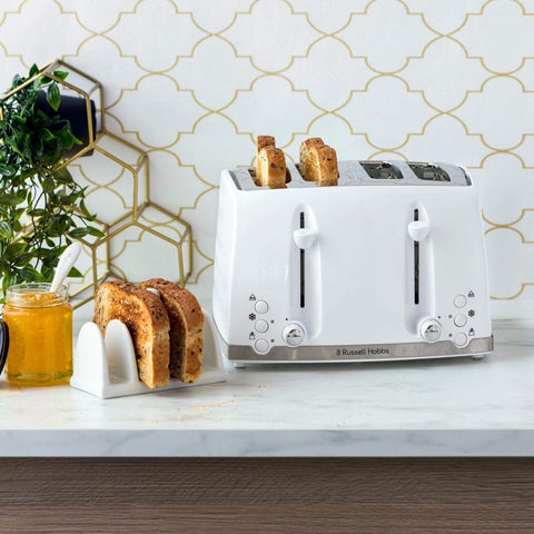 White toaster with slices of bread on a kitchen counter, next to a jar of honey and a plant.