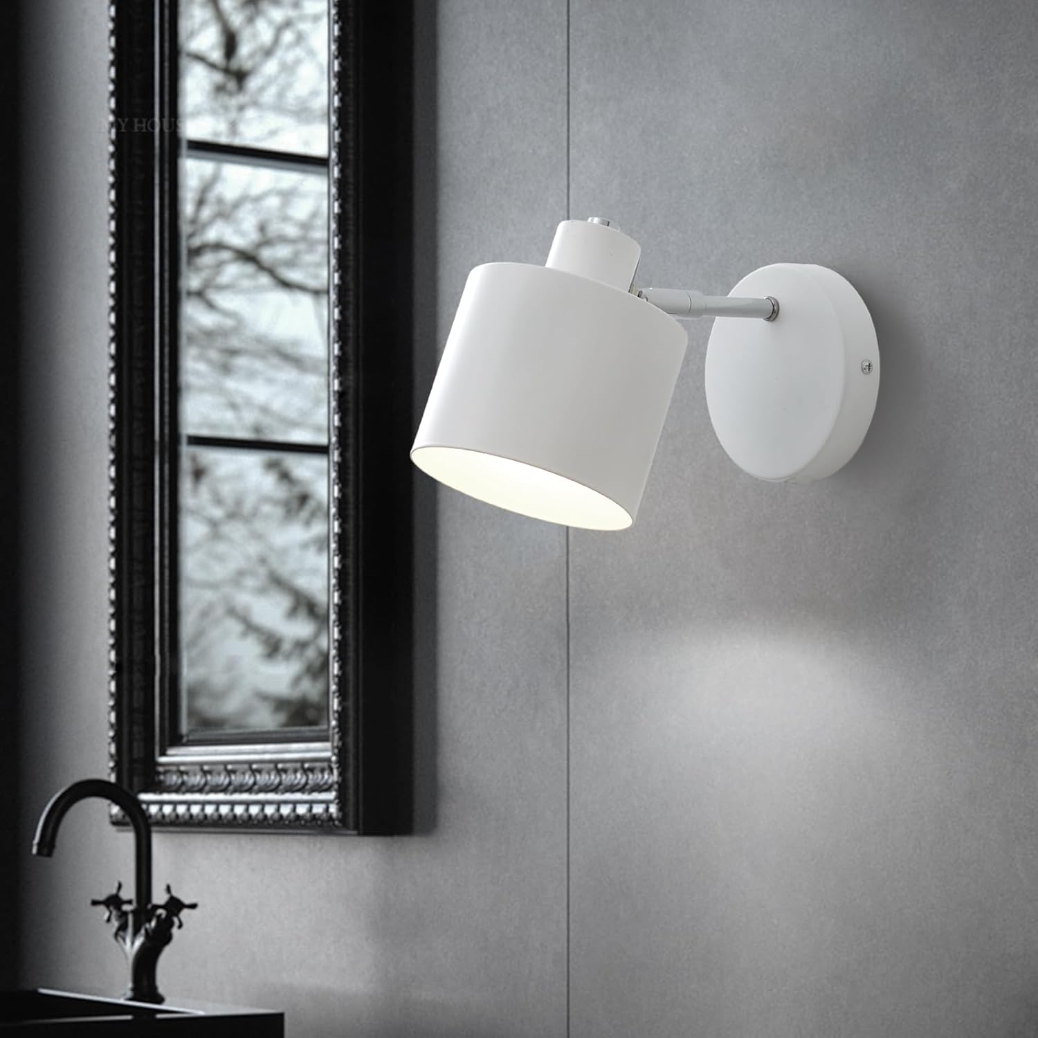 White wall-mounted lamp on a gray wall with a window in the background