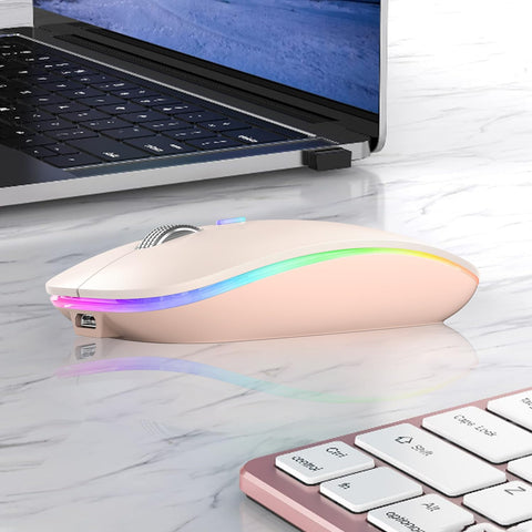 Wireless mouse with RGB lighting on a desk next to a laptop
