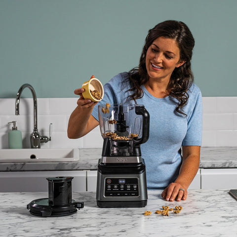 Woman adding ingredients to a blender in a kitchen