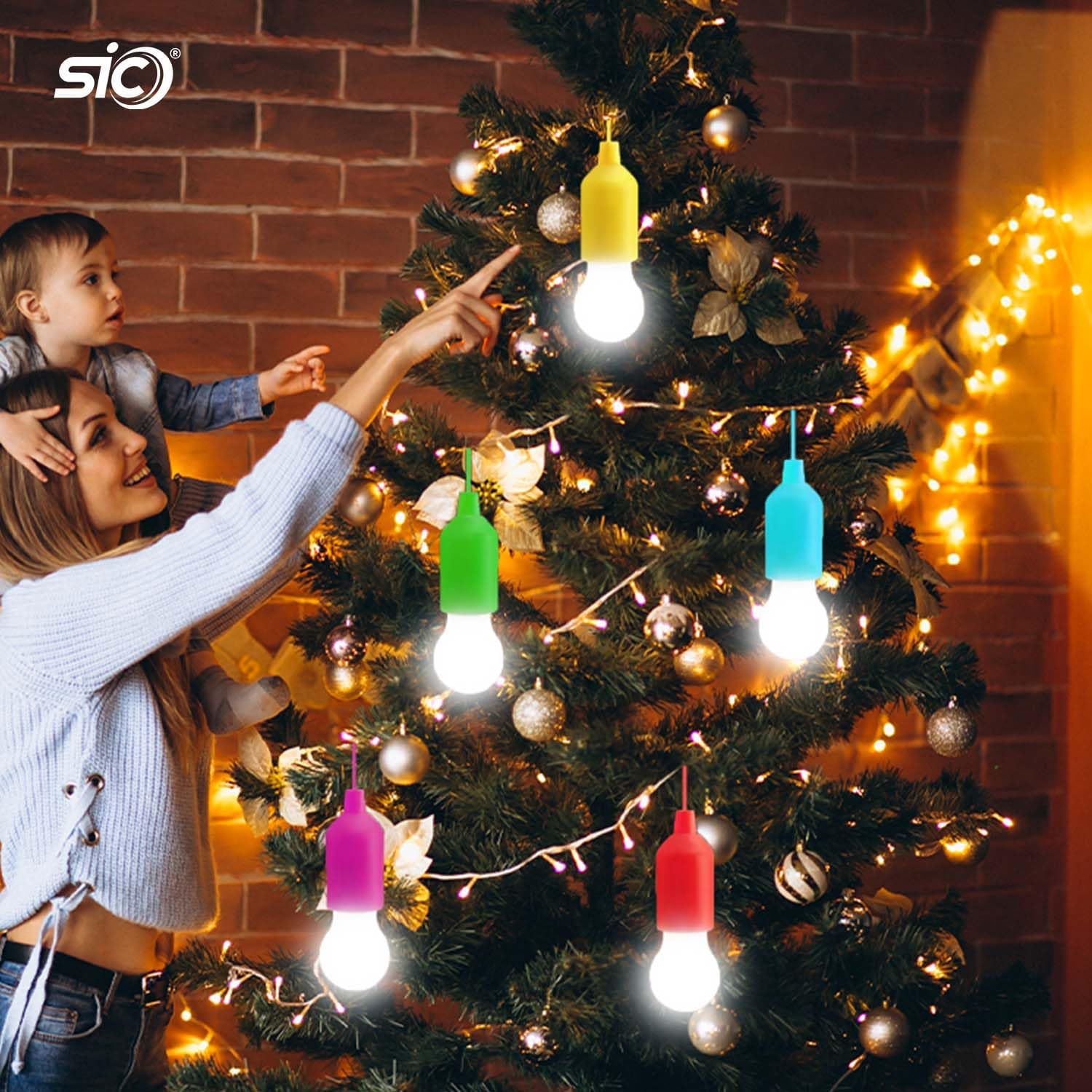Woman and child decorating a Christmas tree with colorful light bulbs.