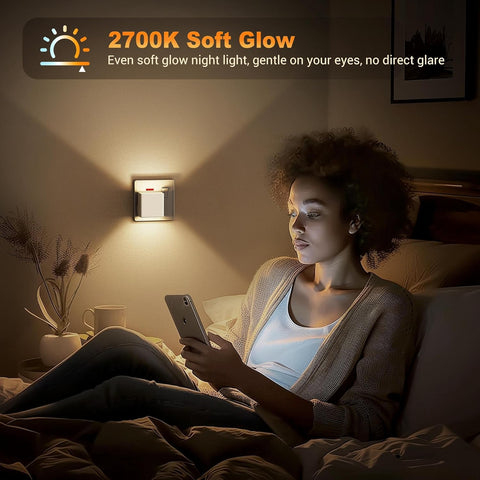 Woman using a smartphone in a dimly lit room with a night light on the wall.