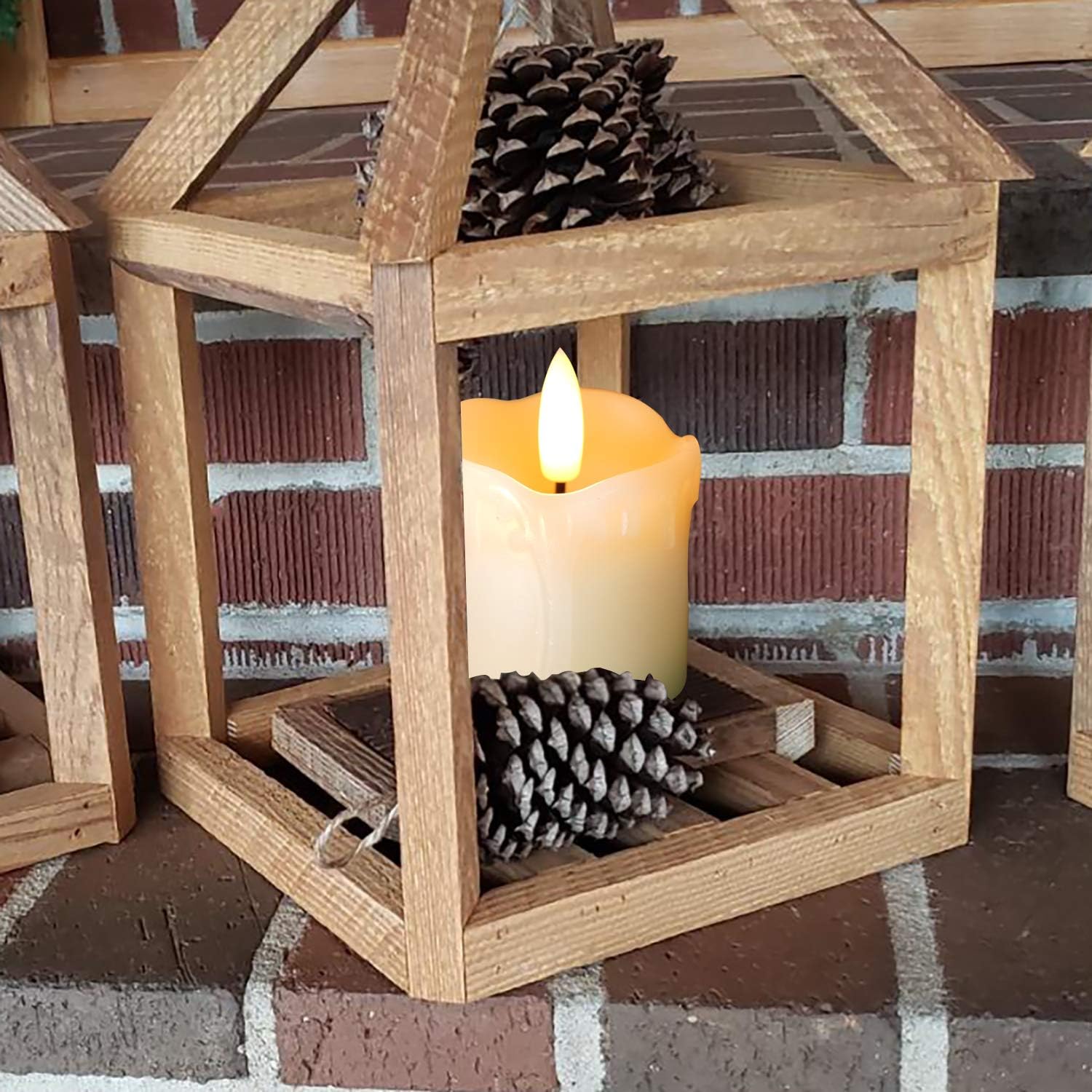 Wooden lantern with a lit candle and pinecones on a brick surface
