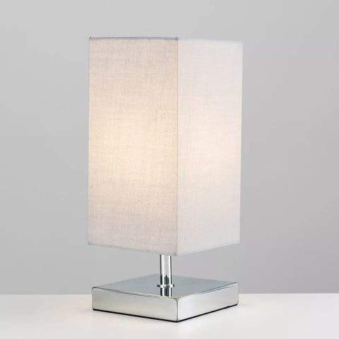 Lamp placed on a modern office desk emitting warm light.​

