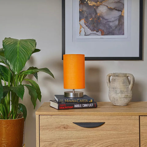 Touch bedside lamp in pink shade on minimalist white cabinet – UK decor trend.


